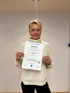 Beate Reinhart mit ihrem Diplom als Wertorientierter Systemischer Aufsteller-Coach (CAS/ISO/ICI), aufgenommen nach dem erfolgreichen Abschluss des Fachlehrgangs. Das Bild steht für Expertise in Konfliktlösung mit systemischer Aufstellung, Mediation und Konfliktberatung..